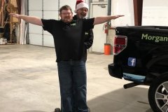 Morgan Miller team having fun in warehouse pushing each other on a dolly with Santa Hat on