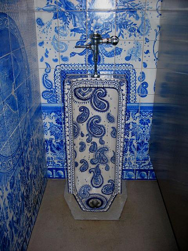 Blue and white paisley patterned ceramic art urinal in a matching tile surround