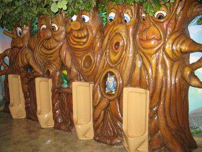 Four urinals set in large humanized tree wall setting